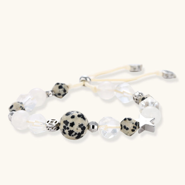 Adjustable beaded bracelet with spotted dalmatian stones, clear quartz crystals, and silver star charm on white background.