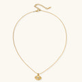 Layered necklace with green stone beads, gold spacers, white accents, and protective eye pendant on cream background.