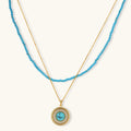 Gold-plated turquoise jewelry set with circular medallion pendant, beaded necklace, and matching stud earrings on white background