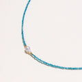 Dainty teal apatite beaded necklace with a single freshwater pearl centerpiece flanked by two small gold beads, adjustable gold clasp.