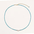Dainty teal apatite beaded necklace with a single freshwater pearl centerpiece flanked by two small gold beads, adjustable gold clasp.